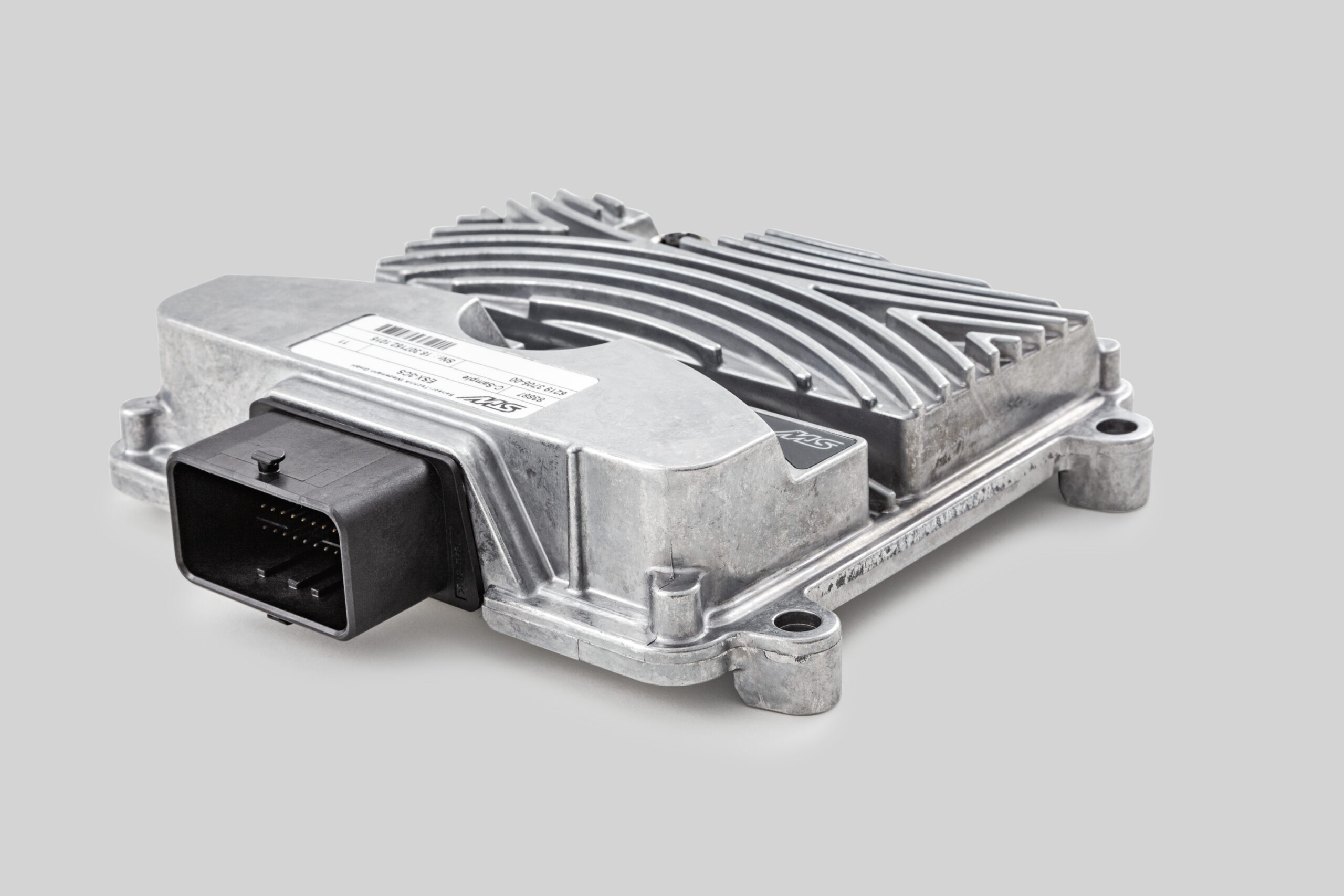 Metal automotive electronic control unit with a ribbed aluminum heat-sink casing and a black multi-pin connector shown on a light gray background, published on www.dasa.se.